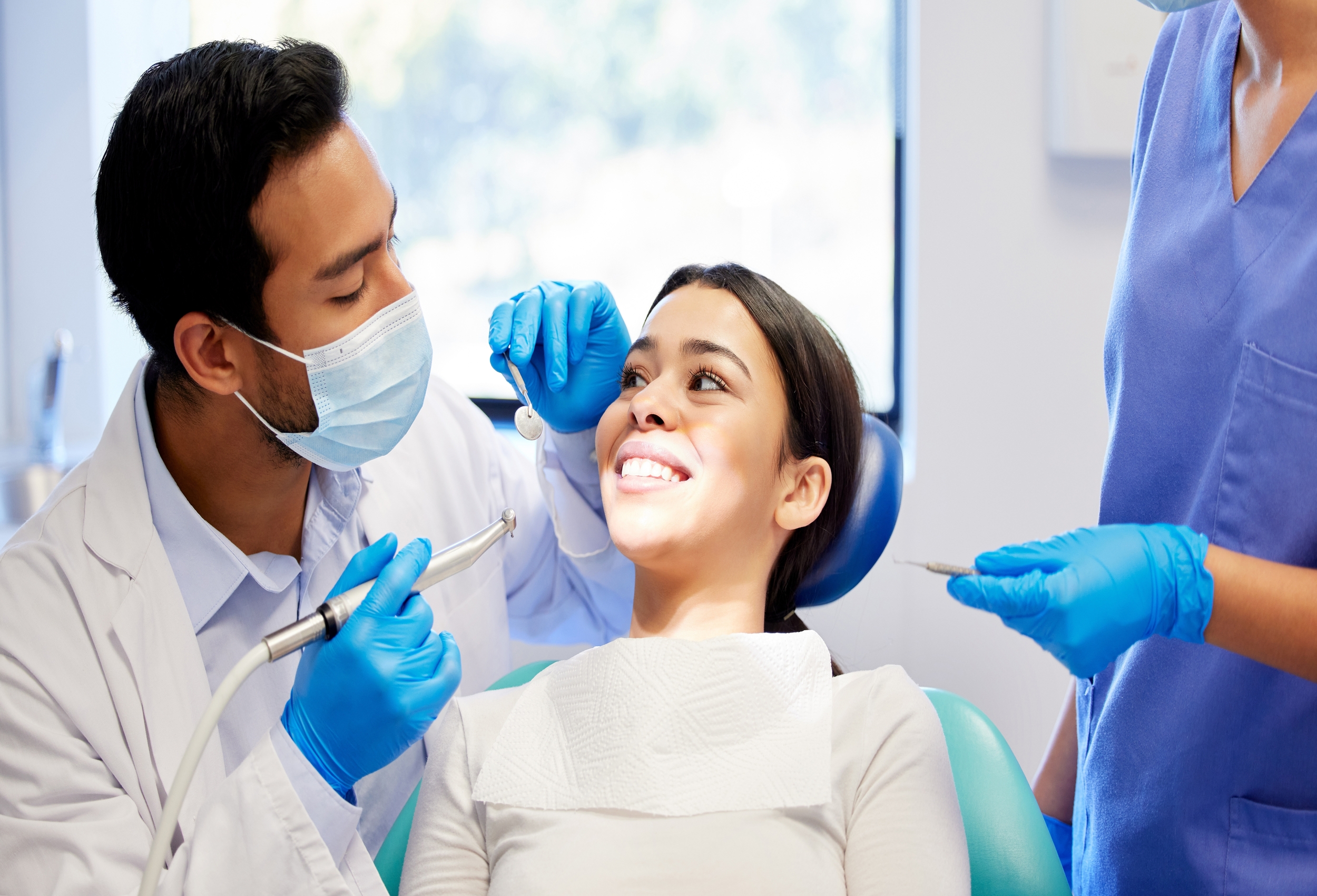 Dentist performing an oral care procedure on a happy patient, focusing on teeth whitening, cleaning, and overall dental wellness in a professional setting