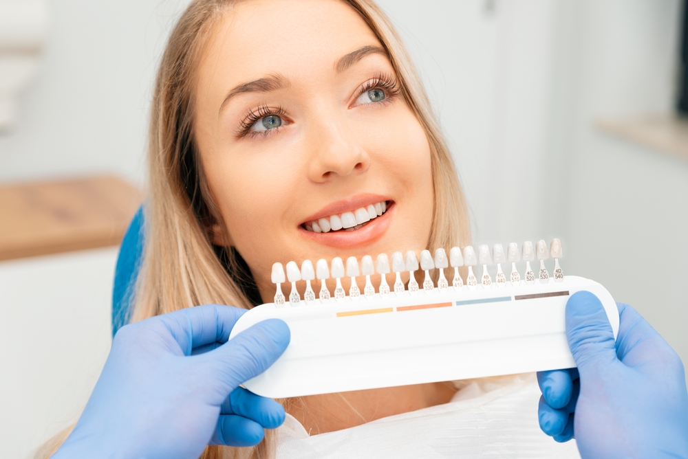 Dentist and patient selecting a shade for dental veneers to match whitened teeth during cosmetic treatment.