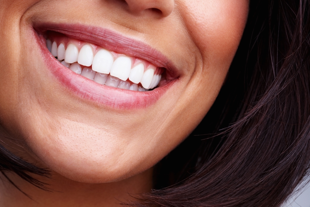 Woman smiling during dental visit, showing healthy teeth and gums after cosmetic dentistry and oral care treatment.